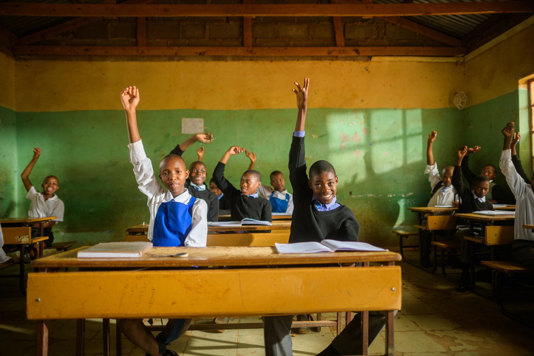 Students in a rural African classroom raising their hands